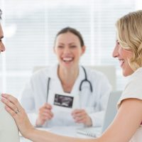 Expectant couple talking while counsulting doctor in clinic